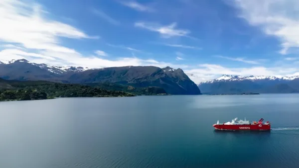 Navimag red ferry sailing through a Patagonian fjord surrounded by snow-capped mountains and blue skies